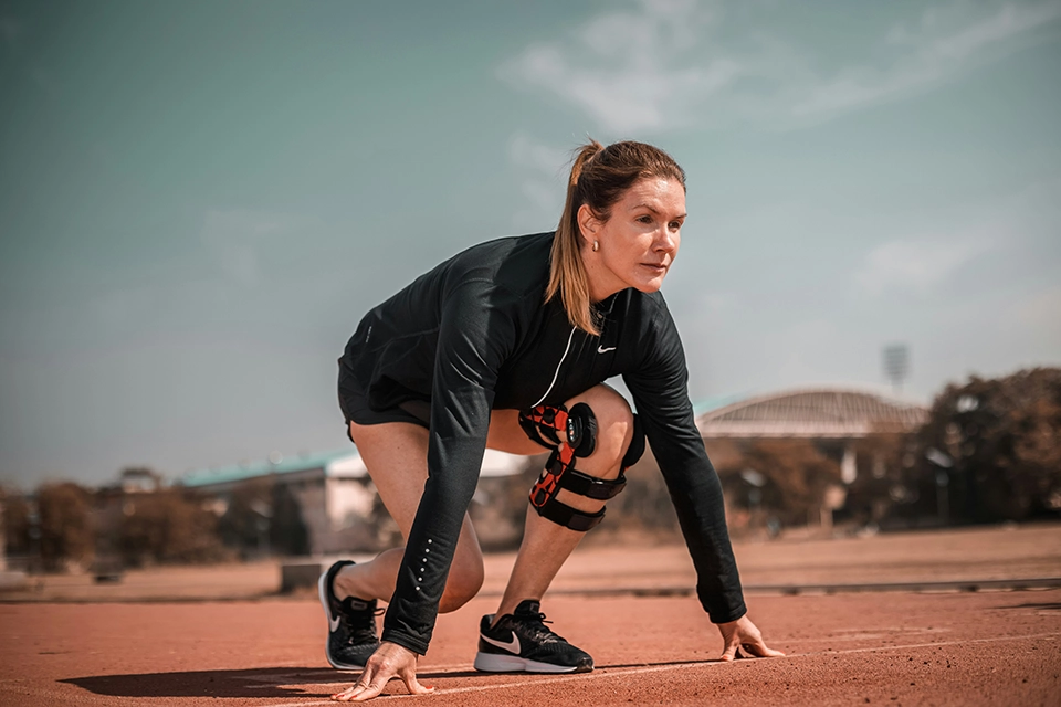 Woman in running position with left knee brace on