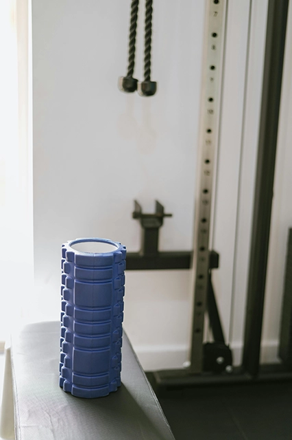 Blue foam roller on a bench with weight room background